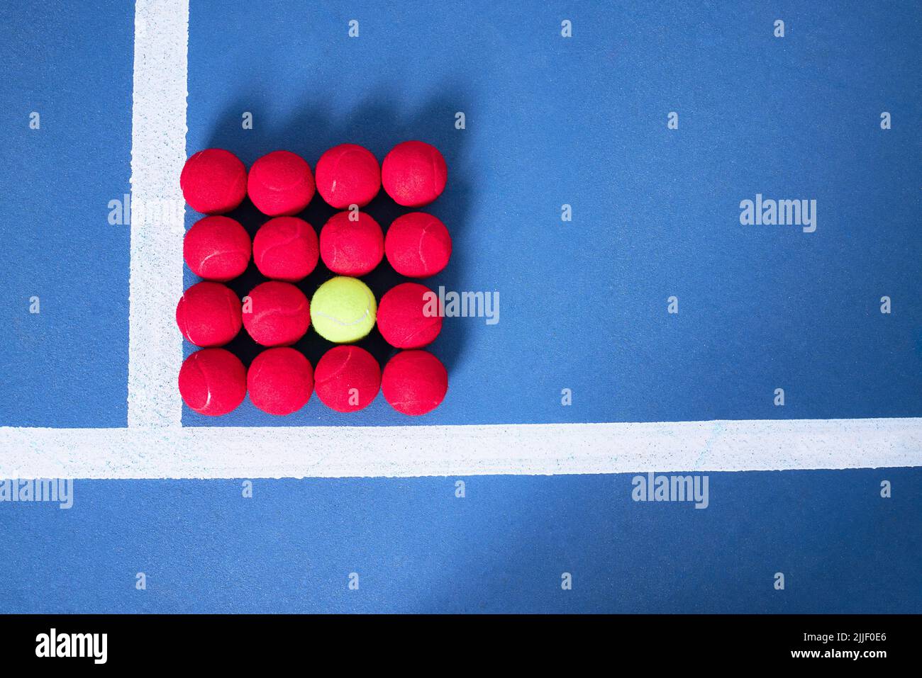 Ce qui vous rend différent, vous rend unique. Plusieurs balles de tennis rouges et une balle de tennis verte formant une place. Banque D'Images