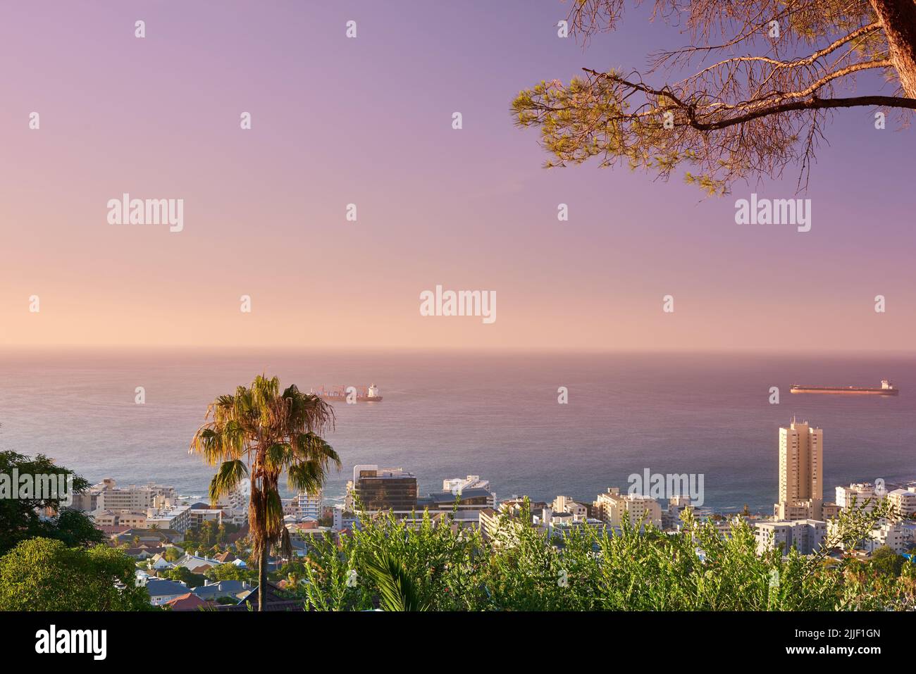 Copiez l'espace, le ciel du coucher du soleil et la vue de la ville sur la mer ou l'océan avec l'infrastructure de bâtiment dans une destination de voyage. Paysage du centre-ville du Cap Banque D'Images