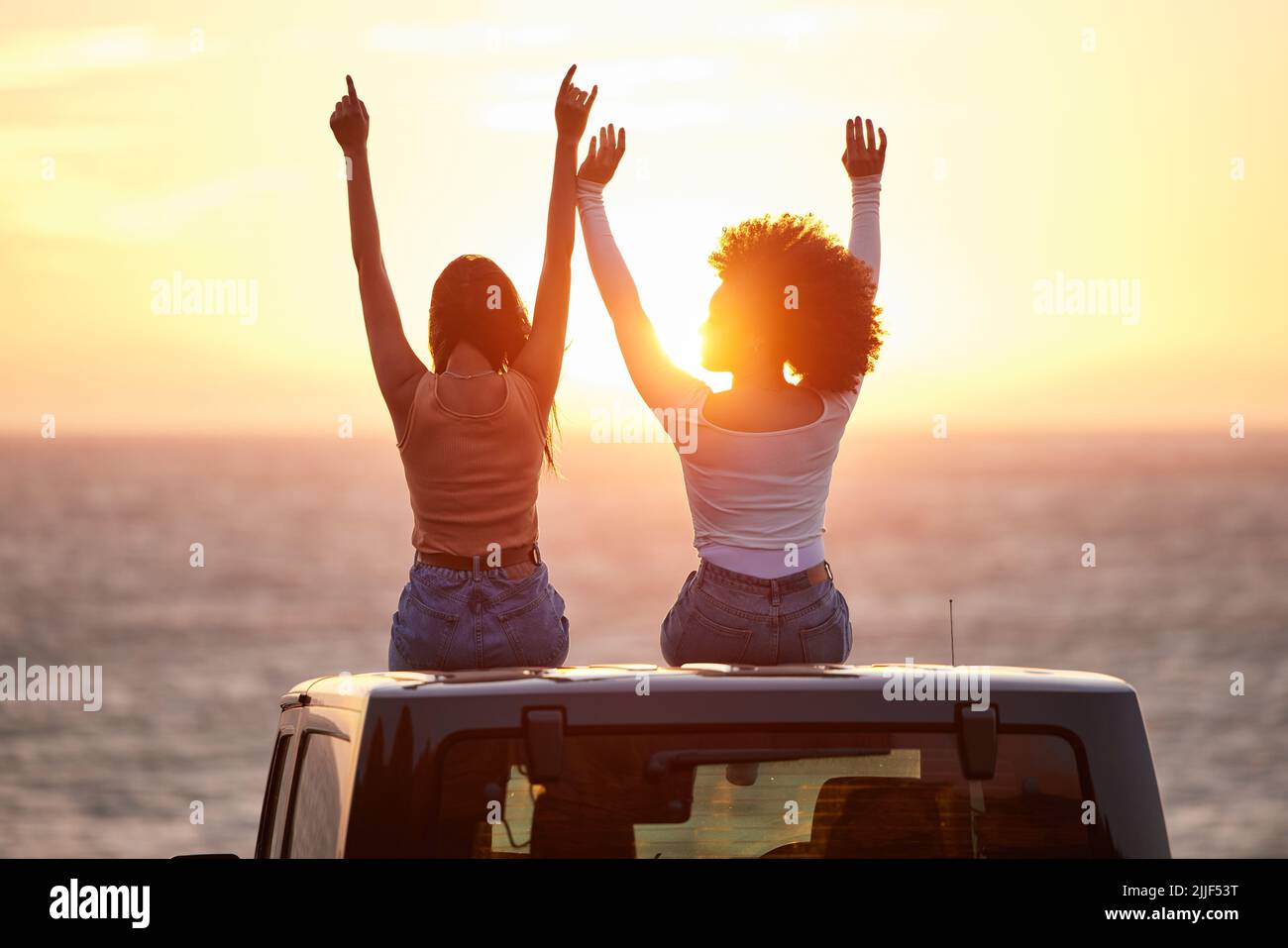 Chantez votre chanson au soleil. Vue arrière de deux jeunes femelles  méconnues célébrant tout en regardant le coucher du soleil sur la plage  Photo Stock - Alamy