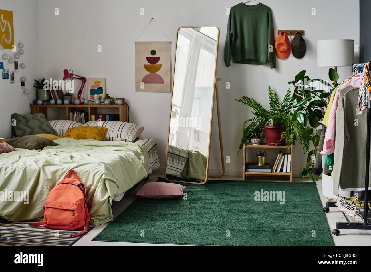 Intérieur élégant de la chambre des adolescents avec lit confortable et vêtements et miroir au centre Banque D'Images