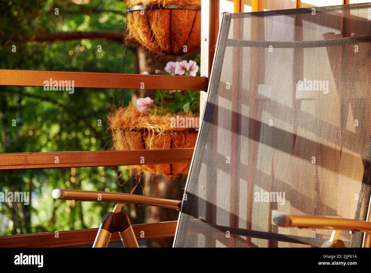 Une chaise confortable sur un balcon éclairé au soleil dans une cabane en forêt. Maisons sauvages et intérieurs Banque D'Images