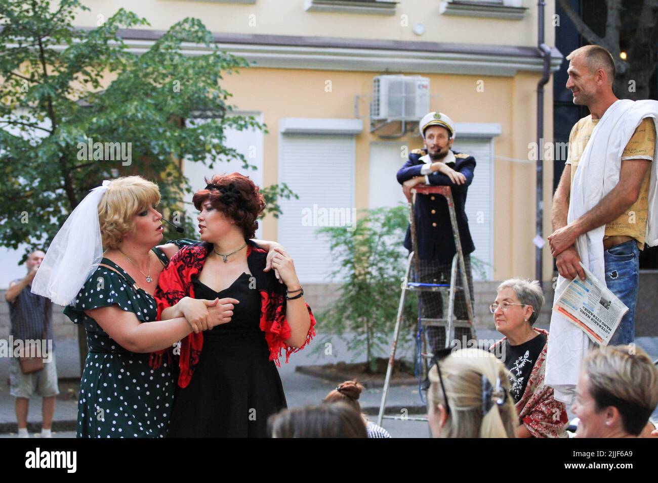 Le public regarde comme acteurs de théâtre exécuter "Odessa, je vous aime" sur le marché du livre à Odessa. La performance "Odessa, je t'aime" raconte des histoires de la vie des habitants d'Odessa avec sa couleur caractéristique et son humour. La représentation a été mise en scène par les acteurs du Théâtre n° 7 et jouée à l'extérieur sur le marché du livre. Le but de cette performance est de recueillir des dons pour les besoins de défense aérienne Banque D'Images