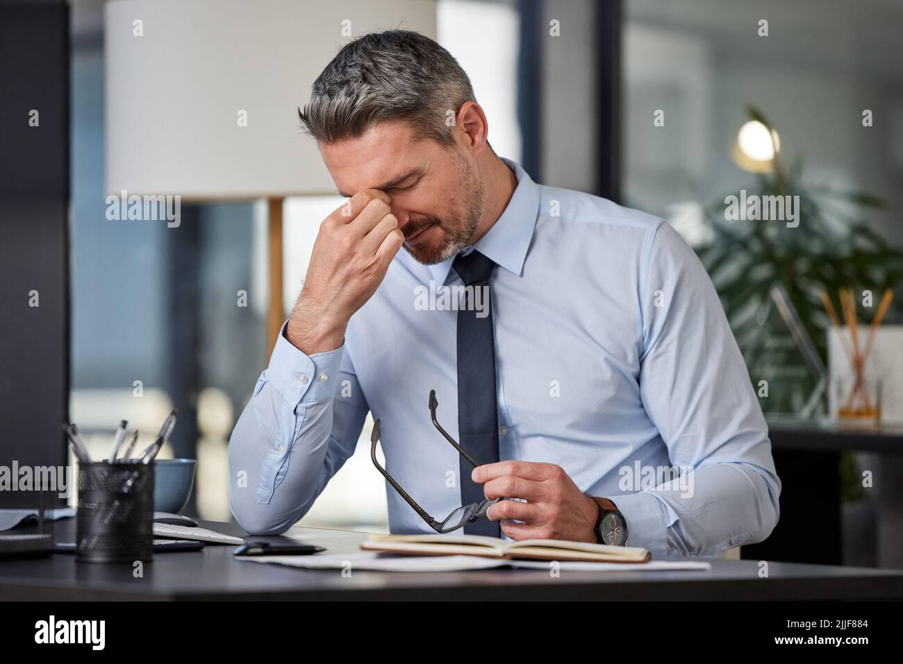 Je n'aurais pas pu sauter le petit déjeuner. Un homme d'affaires mûr qui a eu un mal de tête en s'asseyant à un bureau dans un bureau moderne. Banque D'Images