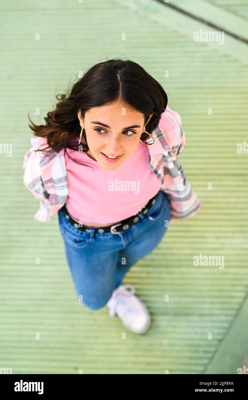 Vue en haut d'une jolie adolescente avec de longs cheveux foncés portant des vêtements tendance décontractés Banque D'Images