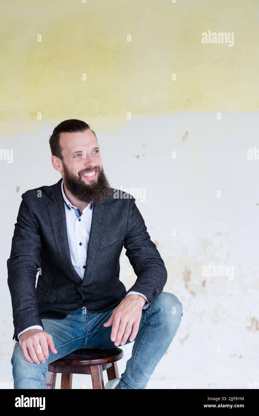 un homme d'affaires sourit assis sur le mur Banque D'Images