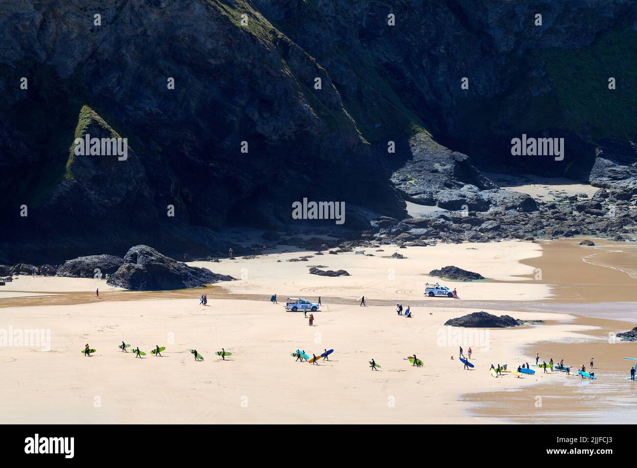 Un groupe de jeunes surfeurs quittent la plage à Mawgan Porth, en Cornouailles, en Angleterre. Banque D'Images