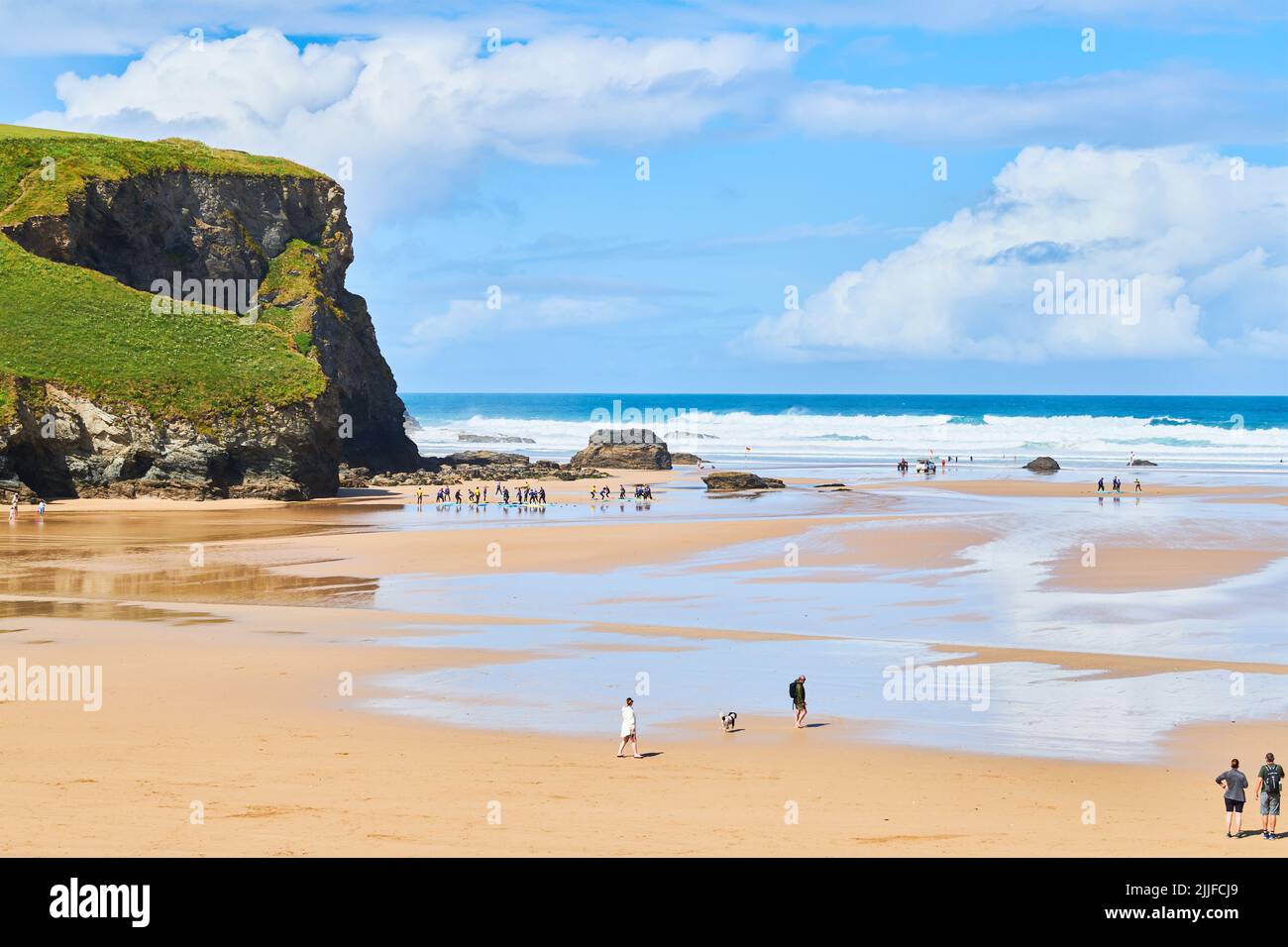 Un groupe de jeunes surfeurs en plein sur la rive de la plage à Mawgan Porth, en Cornouailles, en Angleterre. Banque D'Images