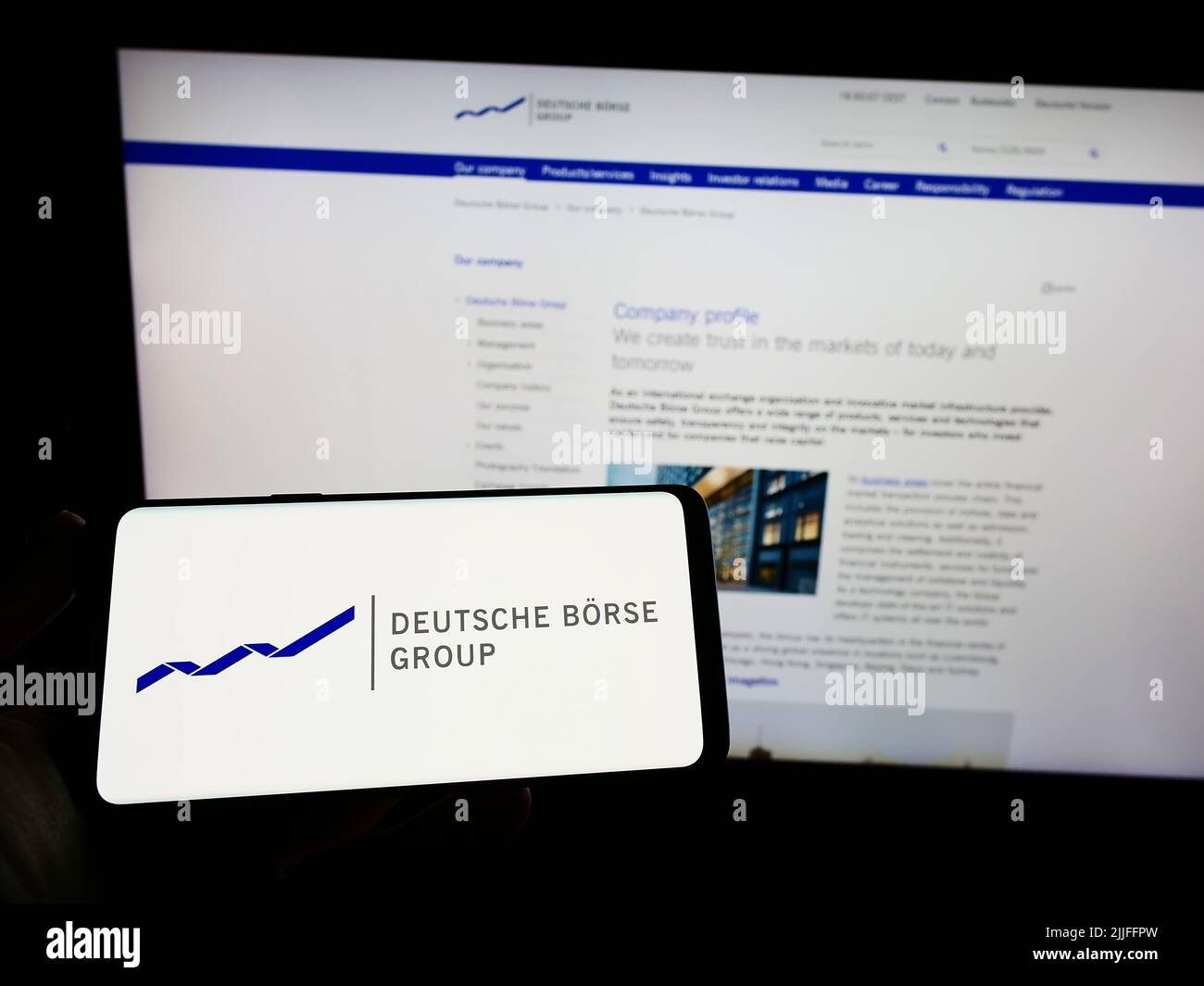 Personne tenant un smartphone avec le logo de la société financière allemande Deutsche Börse AG à l'écran devant le site. Mise au point sur l'affichage du téléphone. Banque D'Images