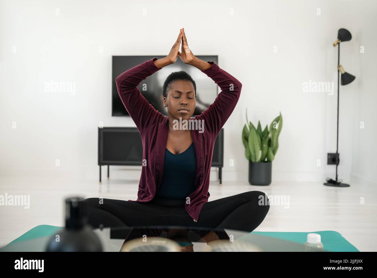 Gros plan de la femme africaine noire assise dans le yoga pose sur tapis dans le salon, étirement et méditation à la maison exercice Banque D'Images