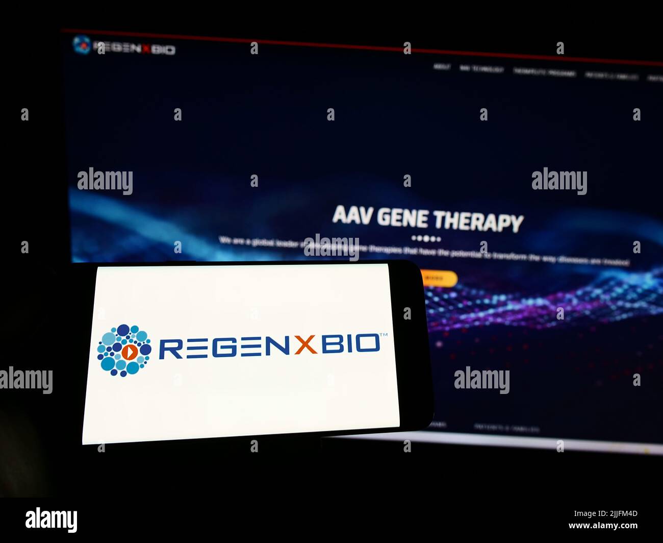 Personne tenant un smartphone avec le logo de la société américaine de biotechnologie Regenxbio Inc. À l'écran devant le site Web. Mise au point sur l'affichage du téléphone. Banque D'Images