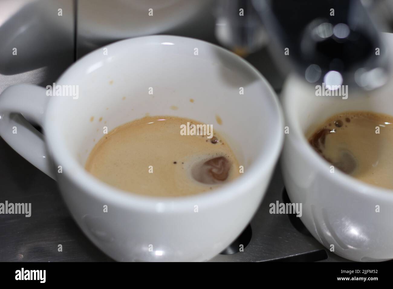 Machine à espresso préparation du café. Un espresso frais s'égoutte dans deux tasses blanches. Café du matin. Banque D'Images