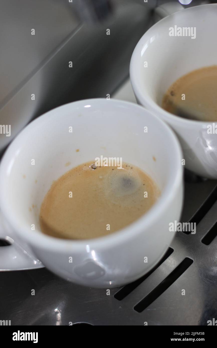 Des espressos fraîchement préparés avec de la mousse de crème fraîchement confectionnés dans des tasses à café en céramique. Préparation du café du matin à la maison. Banque D'Images