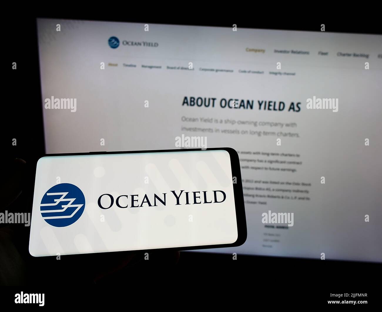 Personne tenant un smartphone avec le logo de la société norvégienne de location de navires Ocean Yield COMME sur l'écran devant le site Web. Mise au point sur l'affichage du téléphone. Banque D'Images