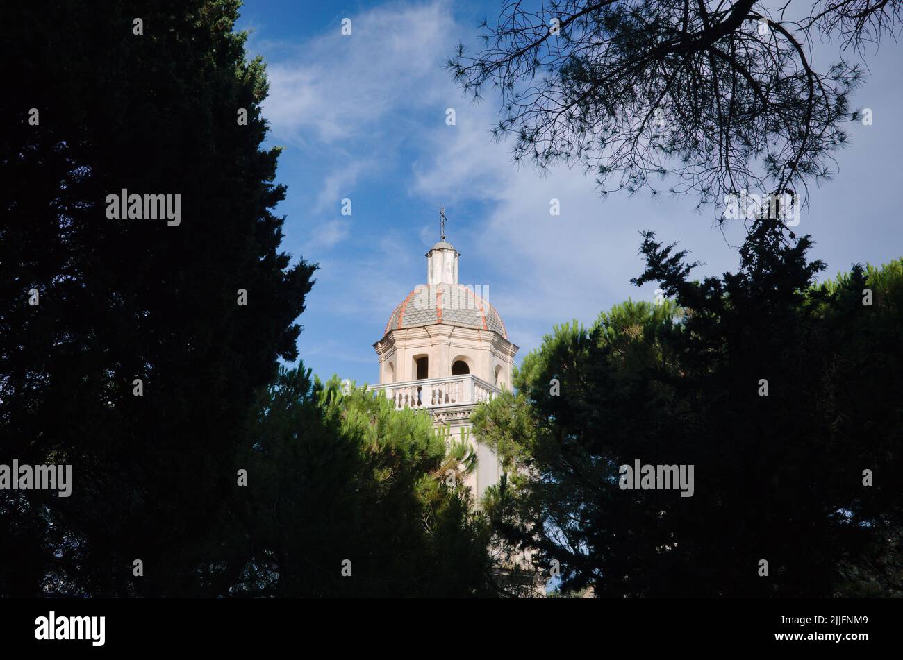 Vue sur le dôme de l'église San Lorenzo entouré de branches d'arbres contre le ciel bleu, Porto Venere, Italie. Dôme de l'église catholique de style romain Banque D'Images