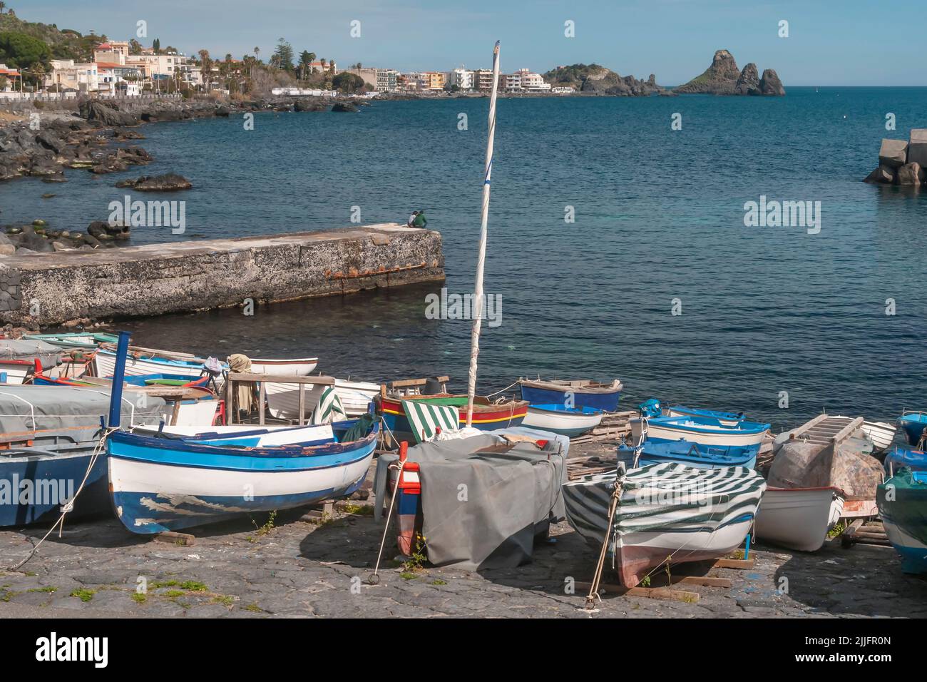 Vieux bateaux en bois sur une plage à ACI Castello, avec ACI Trezza en arrière-plan, Catane, Italie Banque D'Images