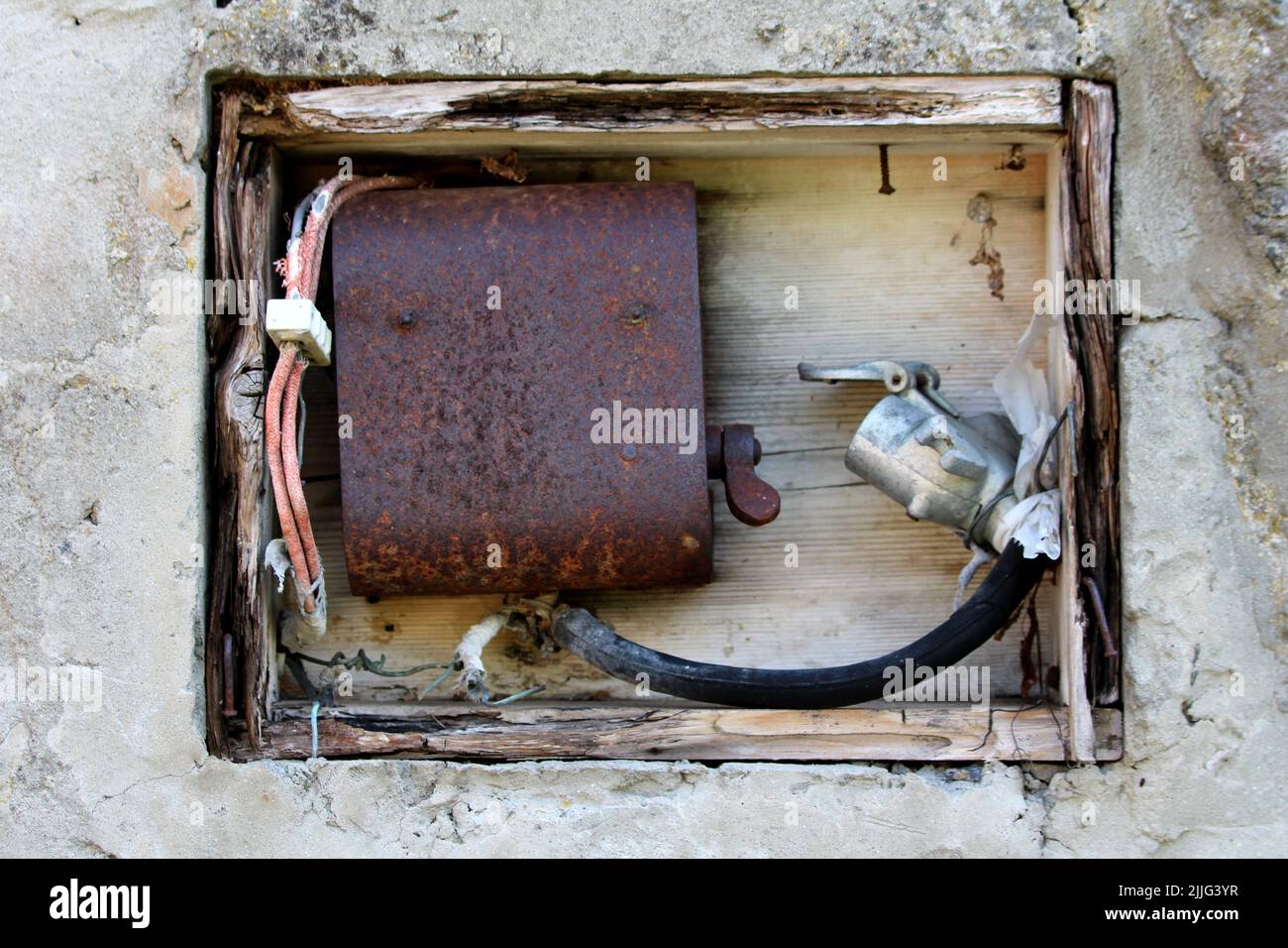 Boîtier électrique en bois ouvert, bâti en bois fissuré rempli de commutateur ancien en métal rouillé et de fils électriques anciens avec un rouge cassé Banque D'Images