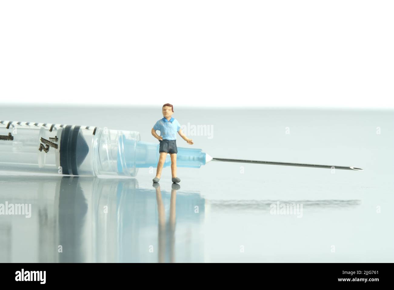 Photographie miniature de personnage de jouet de personnes. Concept de vaccination des enfants. Un garçon debout devant la seringue invite à se faire vacciner. Photo d'image Banque D'Images