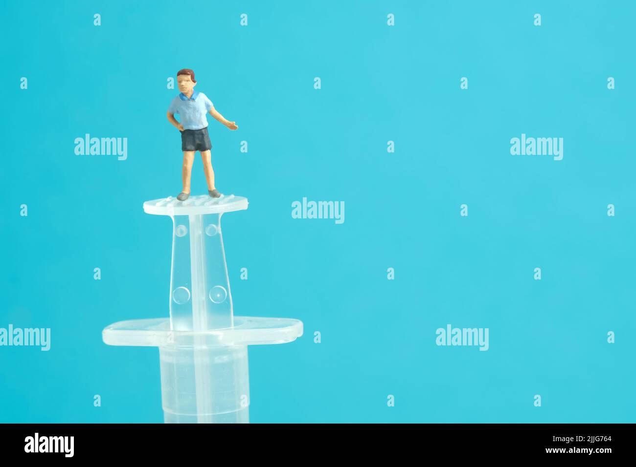 Photographie miniature de personnage de jouet de personnes. Concept de vaccination des enfants. Un garçon debout au-dessus de la seringue invite à se faire vacciner. Photo d'image Banque D'Images