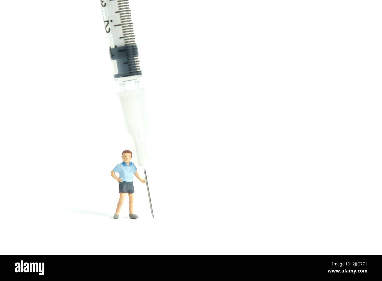 Photographie miniature de personnage de jouet de personnes. Concept de vaccination des enfants. Un garçon debout à côté de la seringue invite à se faire vacciner. Photo d'image Banque D'Images