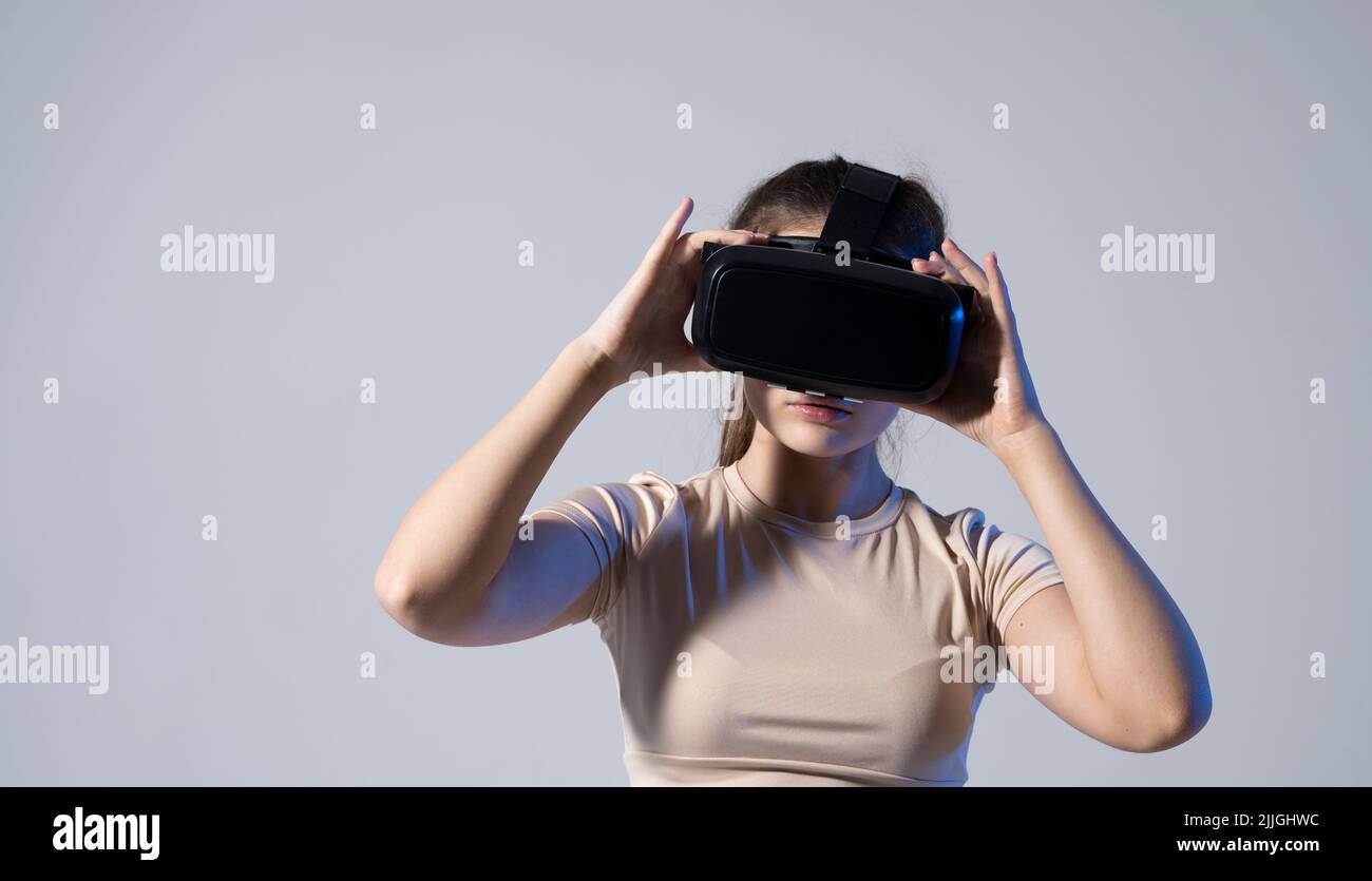 Brunette femme joueur avec une réalité virtuelle lunettes prêt à jouer un jeu ou explorer l'environnement dans un monde métaverse. Technologies modernes. Banque D'Images