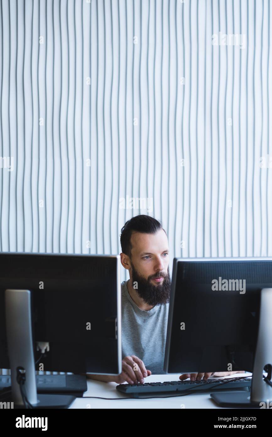 homme de travail deux moniteurs ont été barbus spécialiste de l'informatique Banque D'Images