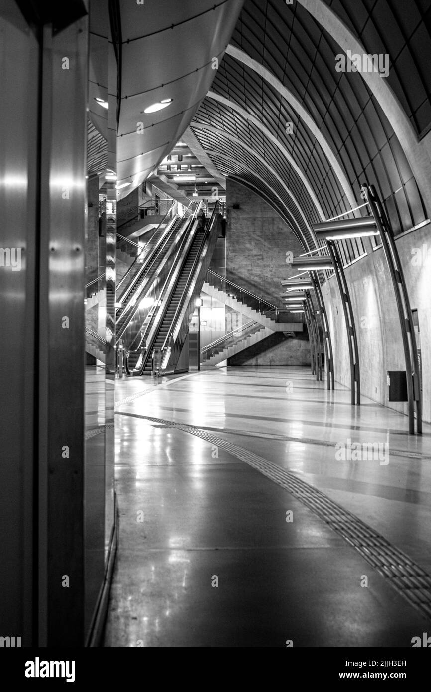 Une photo verticale en niveaux de gris d'un centre commercial souterrain vide avec escaliers roulants en arrière-plan Banque D'Images