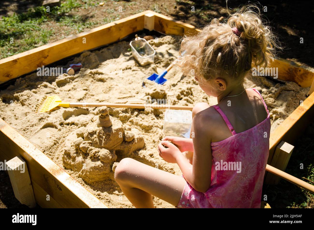 adorable fille blonde s'amuser avec le sable dans l'aire de jeux Banque D'Images
