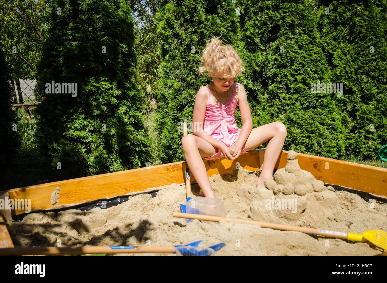 adorable fille blonde s'amuser avec le sable dans l'aire de jeux Banque D'Images