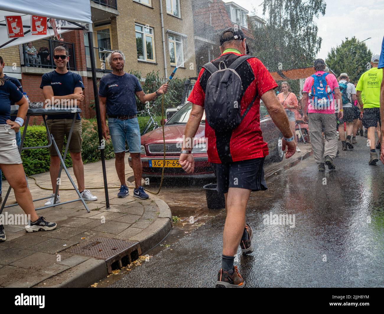 Un homme est vu jeter de l'eau aux marcheurs en raison des températures élevées pendant le plus grand événement de marche de plusieurs jours au monde. La marche des quatre jours (en néerlandais 'Vierdaagse') est considérée comme le premier exemple de l'esprit sportif et des liens internationaux entre militaires et civils de nombreux pays différents. Après deux ans d'annulation, il a été retenu à nouveau, mais le premier jour a été annulé en raison de températures chaudes, transformant les quatre marches en trois jours de marche. Il s'agit de l'édition 104 et le total officiel des marcheurs enregistrés était de 38 455 dans 69 pays. Ils peuvent choisir de marcher 30k Banque D'Images