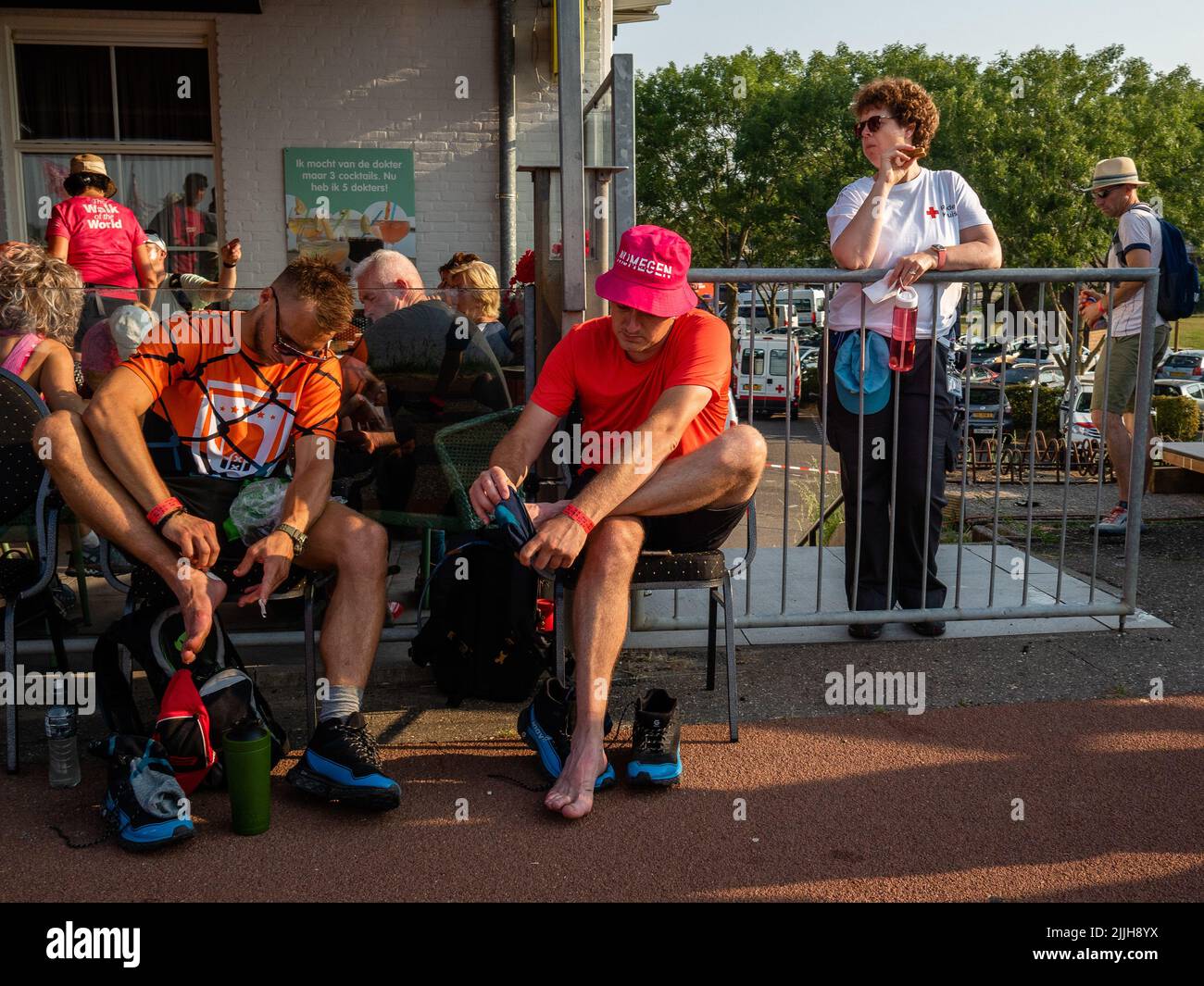 Deux marcheurs massent leurs pieds lors du plus grand événement de randonnée de plusieurs jours au monde. La marche des quatre jours (en néerlandais 'Vierdaagse') est considérée comme le premier exemple de l'esprit sportif et des liens internationaux entre militaires et civils de nombreux pays différents. Après deux ans d'annulation, il a été retenu à nouveau, mais le premier jour a été annulé en raison de températures chaudes, transformant les quatre marches en trois jours de marche. Il s'agit de l'édition 104 et le total officiel des marcheurs enregistrés était de 38 455 dans 69 pays. Ils peuvent choisir de marcher 30km, 40km ou 50km par jour. Banque D'Images