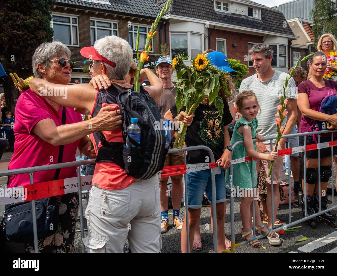 Une femme reçoit du gladiolus d'un ami lors du plus grand événement de marche de plusieurs jours au monde. La marche des quatre jours (en néerlandais 'Vierdaagse') est considérée comme le premier exemple de l'esprit sportif et des liens internationaux entre militaires et civils de nombreux pays différents. Après deux ans d'annulation, il a été retenu à nouveau, mais le premier jour a été annulé en raison de températures chaudes, transformant les quatre marches en trois jours de marche. Il s'agit de l'édition 104 et le total officiel des marcheurs enregistrés était de 38 455 dans 69 pays. Ils peuvent choisir de marcher 30km, 40km, ou 50km par da Banque D'Images