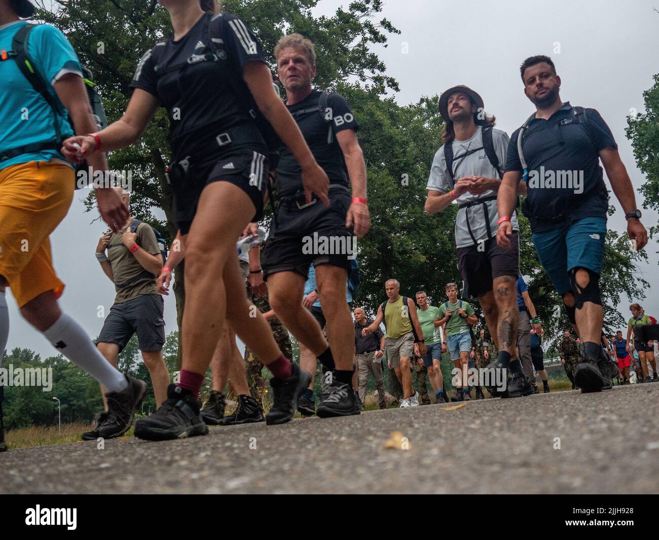 Les participants marchent très tôt le matin lors du plus grand événement de marche de plusieurs jours au monde. La marche des quatre jours (en néerlandais 'Vierdaagse') est considérée comme le premier exemple de l'esprit sportif et des liens internationaux entre militaires et civils de nombreux pays différents. Après deux ans d'annulation, il a été retenu à nouveau, mais le premier jour a été annulé en raison de températures chaudes, transformant les quatre marches en trois jours de marche. Il s'agit de l'édition 104 et le total officiel des marcheurs enregistrés était de 38 455 dans 69 pays. Ils peuvent choisir de marcher 30km, 40km ou 50km par jour. Banque D'Images