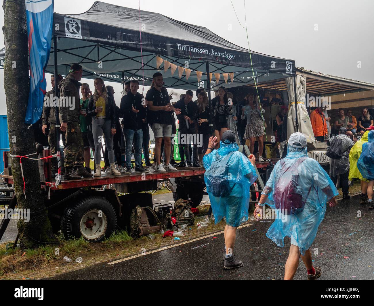 Les gens applaudissent les marcheurs de l'intérieur d'un camion lors du plus grand événement de randonnée de plusieurs jours au monde. La marche des quatre jours (en néerlandais 'Vierdaagse') est considérée comme le premier exemple de l'esprit sportif et des liens internationaux entre militaires et civils de nombreux pays différents. Après deux ans d'annulation, il a été retenu à nouveau, mais le premier jour a été annulé en raison de températures chaudes, transformant les quatre marches en trois jours de marche. Il s'agit de l'édition 104 et le total officiel des marcheurs enregistrés était de 38 455 dans 69 pays. Ils peuvent choisir de marcher 30km, 40km ou 50km par Banque D'Images