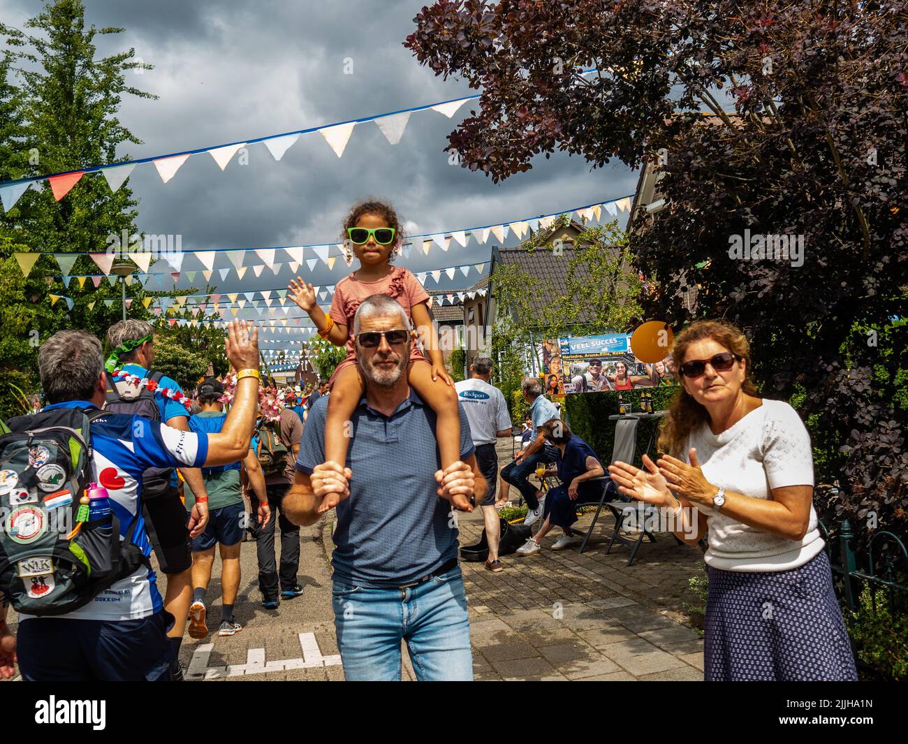 Un père est vu tenir sa fille sur ses épaules pendant qu'il regarde les marcheurs passer pendant le plus grand événement de marche de plusieurs jours au monde. La marche des quatre jours (en néerlandais 'Vierdaagse') est considérée comme le premier exemple de l'esprit sportif et des liens internationaux entre militaires et civils de nombreux pays différents. Après deux ans d'annulation, il a été retenu à nouveau, mais le premier jour a été annulé en raison de températures chaudes, transformant les quatre marches en trois jours de marche. Il s'agit de l'édition 104 et le total officiel des marcheurs enregistrés était de 38 455 dans 69 pays. Ils c Banque D'Images