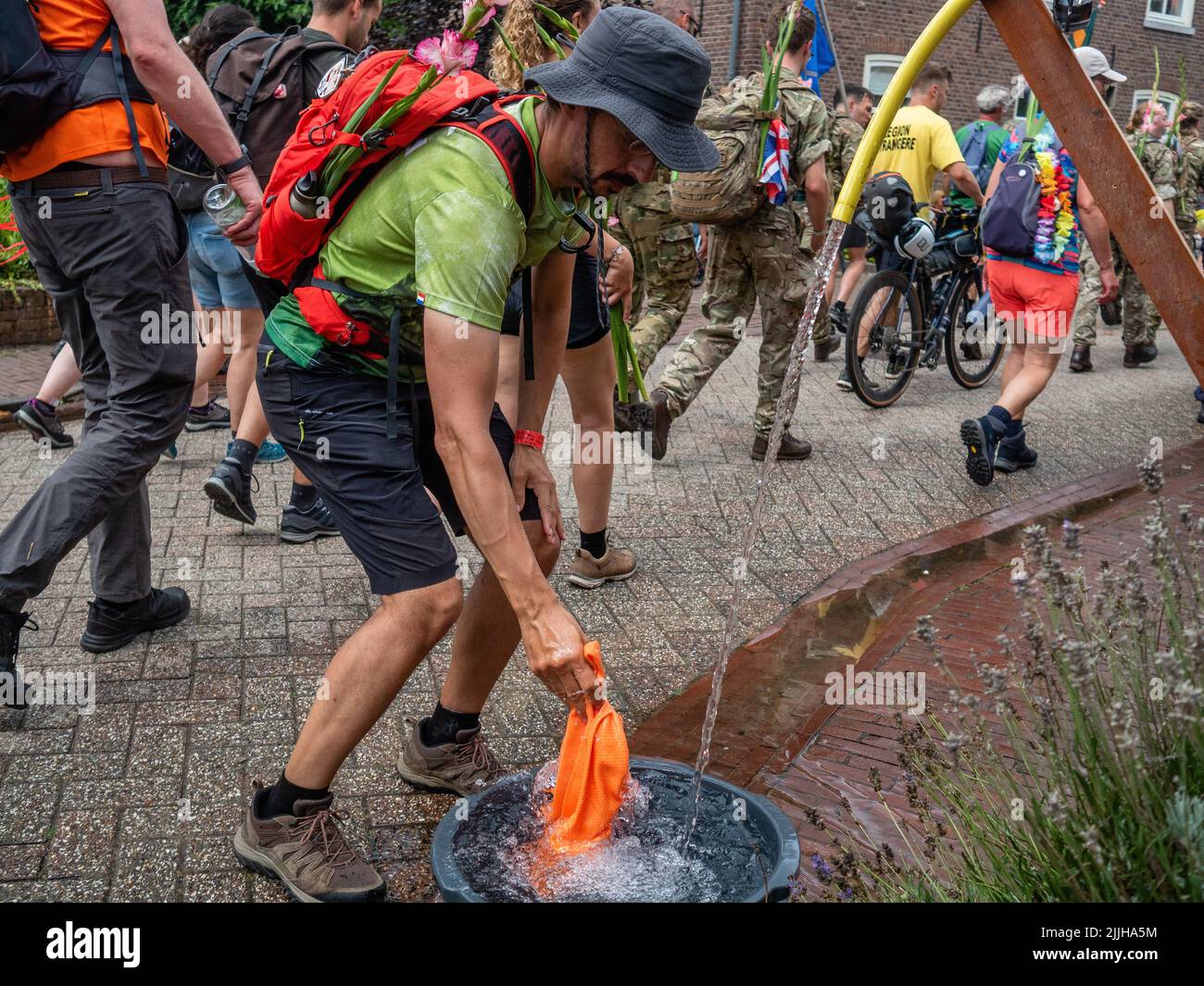 Un homme rafraîchit sa serviette dans l'eau froide en raison des températures chaudes pendant le plus grand événement de marche de plusieurs jours au monde. La marche des quatre jours (en néerlandais 'Vierdaagse') est considérée comme le premier exemple de l'esprit sportif et des liens internationaux entre militaires et civils de nombreux pays différents. Après deux ans d'annulation, il a été retenu à nouveau, mais le premier jour a été annulé en raison de températures chaudes, transformant les quatre marches en trois jours de marche. Il s'agit de l'édition 104 et le total officiel des marcheurs enregistrés était de 38 455 dans 69 pays. Ils peuvent choisir de marcher 30k Banque D'Images