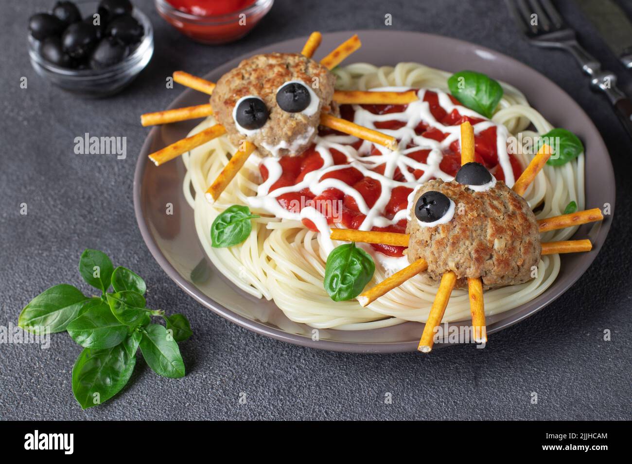Les côtelettes ressemblent à des araignées aux olives et aux pailles, servies avec des pâtes spaghetti et de la sauce tomate. Idée petit déjeuner Halloween Banque D'Images