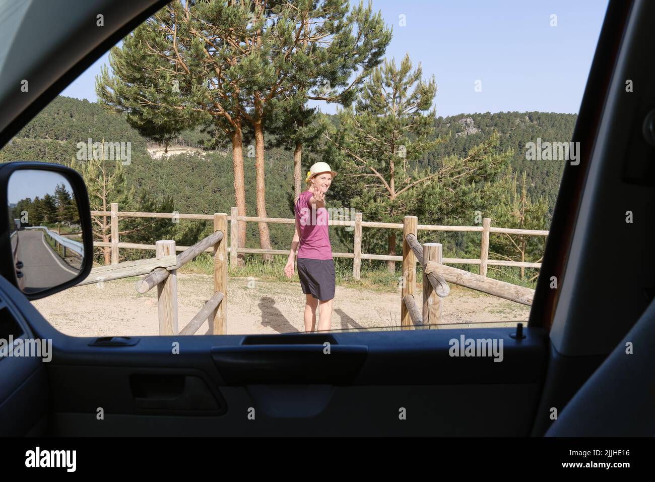 Femme faisant venir ici geste près de la voiture dans la campagne Banque D'Images