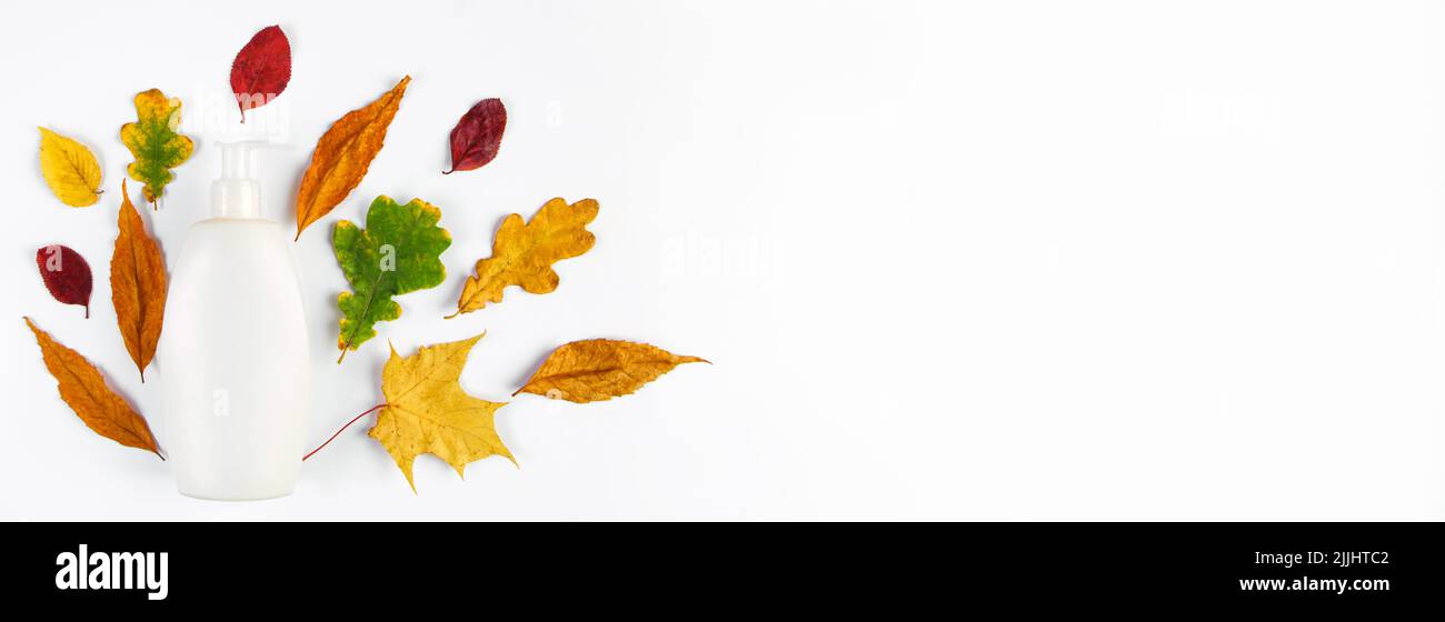 Bouteille cosmétique blanche et feuilles jaunes d'automne. Concept de soin de la peau d'automne. Design minimaliste de cosmétiques écologiques. Copier l'espace. Banque D'Images