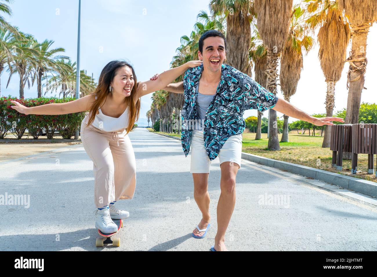 Jeune couple diversifié avec skateboard et longue planche à roulettes s'amuser en plein air. Banque D'Images