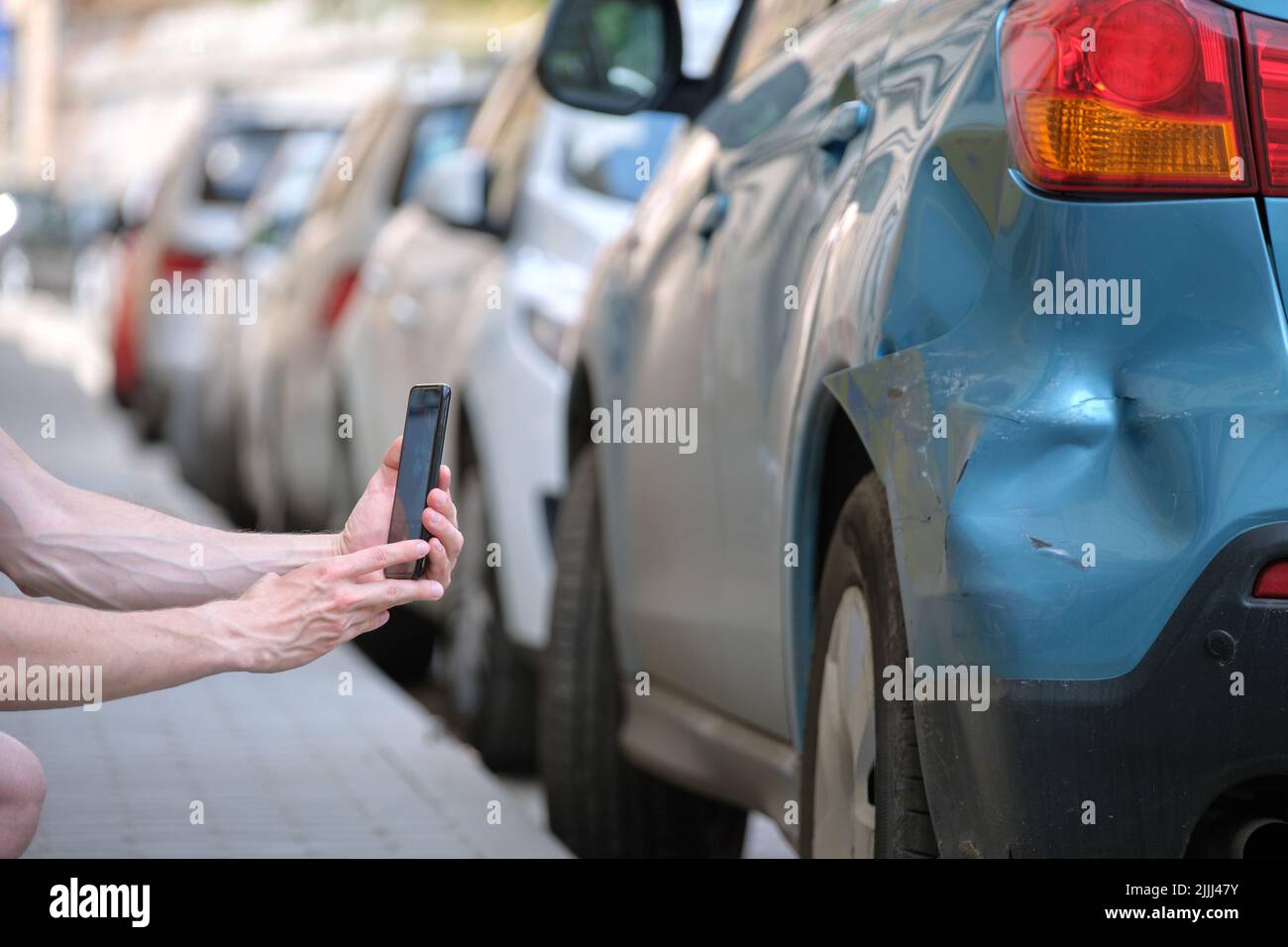 Un conducteur stressé prend des photos sur l'appareil photo du téléphone du véhicule écrasé en appelant le service d'urgence après un accident de voiture.Sécurité routière et assurance Banque D'Images