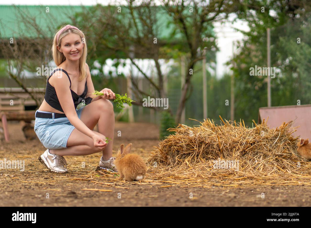 La fille nourrit le persil brun lapin pâques lapin blanc fond de jardin, pour mignon jeune dans la nature de l'herbe d'été, beau animal. Drôle peu, Banque D'Images