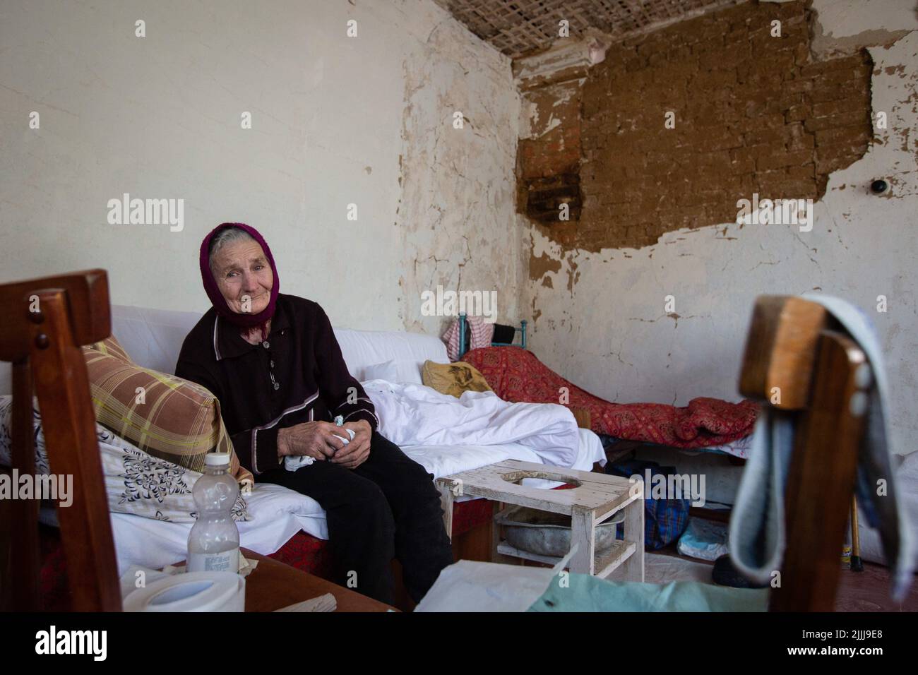 Une femme âgée s'assoit sur un lit dans une maison détruite par l'artillerie russe. La Russie a envahi l'Ukraine sur 24 février 2022. Banque D'Images