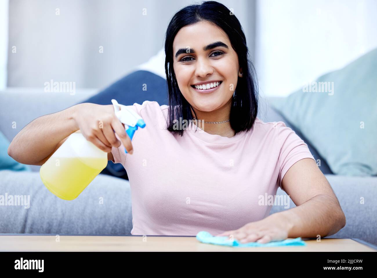 Il a juste besoin d'une bonne lingette. Une jeune femme nettoyant une table à la maison. Banque D'Images