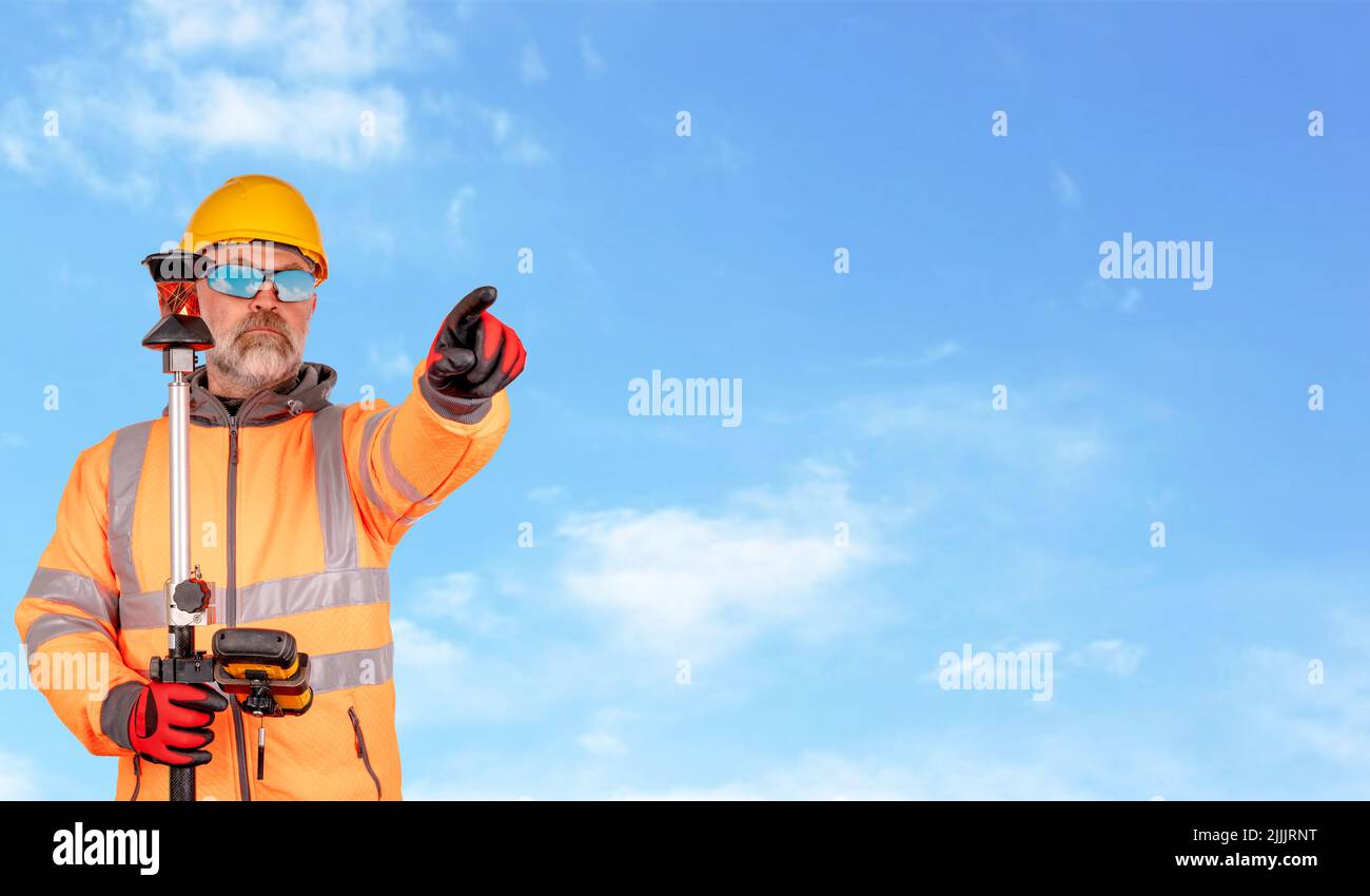 Un constructeur dans un chapeau et un polaire orange réfléchissant dans des lunettes de sécurité donne un mouvement de direction sur fond blanc avec de l'espace pour le texte sur fond ciel Banque D'Images