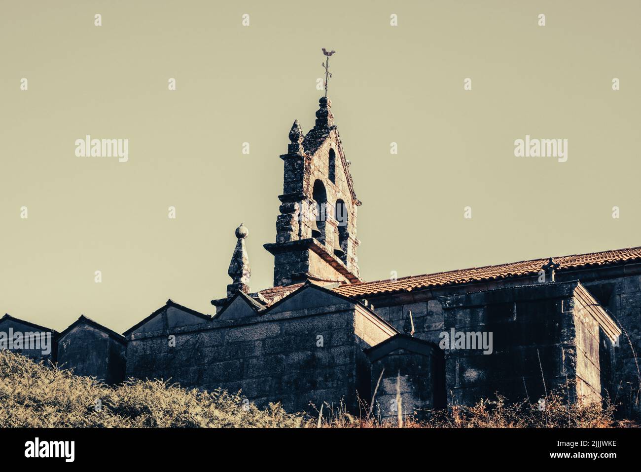 Détail de l'église et cimetière d'un village galicien sous le coucher du soleil d'une colline. Banque D'Images