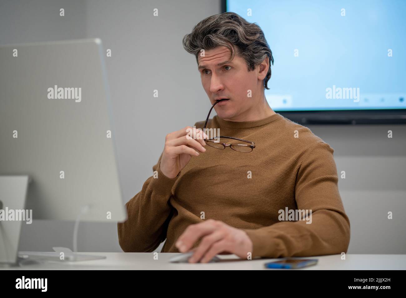 Un homme assis à l'ordinateur et regardant concentré Banque D'Images