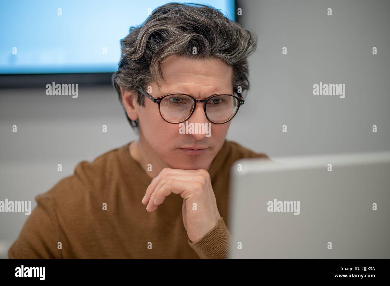 Un homme assis à l'ordinateur et regardant concentré Banque D'Images