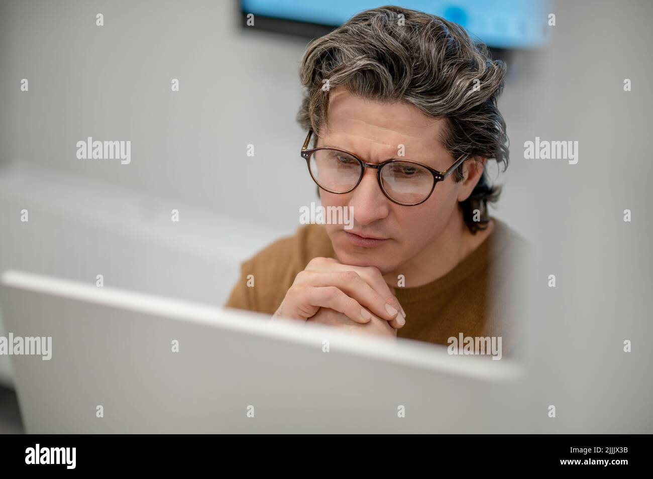 Un homme assis à l'ordinateur et regardant concentré Banque D'Images