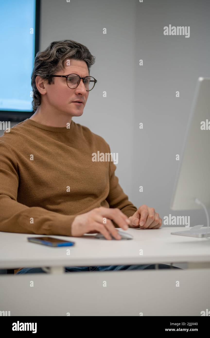 Un homme assis à l'ordinateur et regardant concentré Banque D'Images