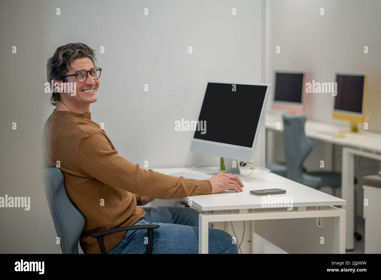 Un homme aux cheveux sombres assis à l'ordinateur et regardant impliqué Banque D'Images